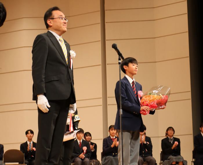 写真：表彰式で酒井市長から花束を受け取る横田さん