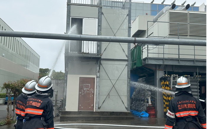 立川市消防団員が放水している様子を後ろから写したもの