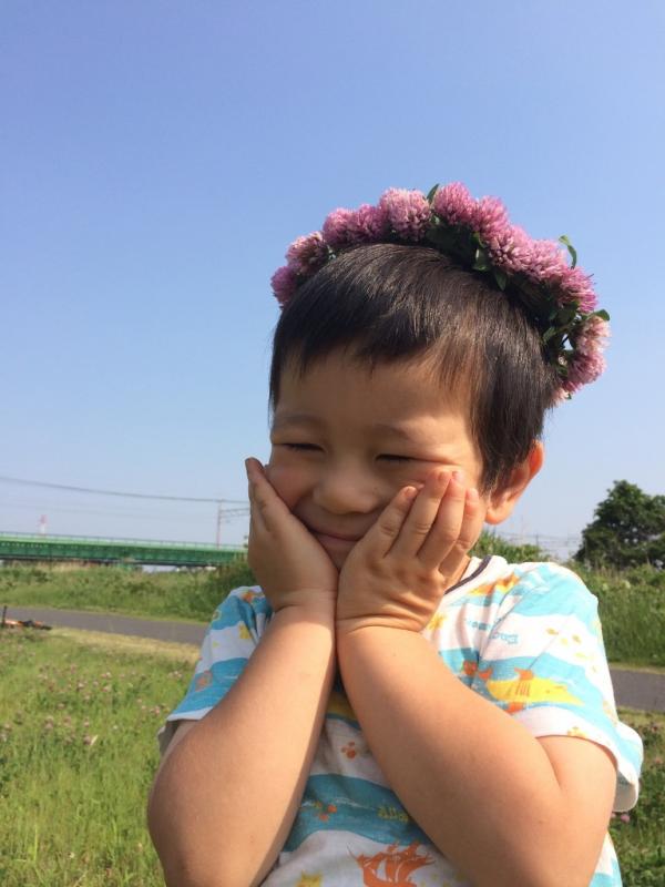 子供が花かざりを頭につけて、両手を顎に置き、うっとりとした顔の写真